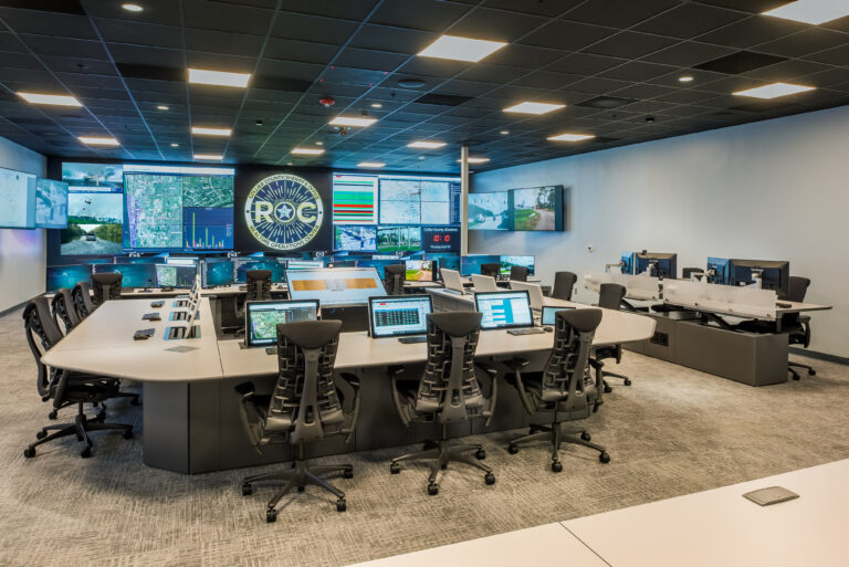 a large room of computers and desks with a ROC logo on the wall