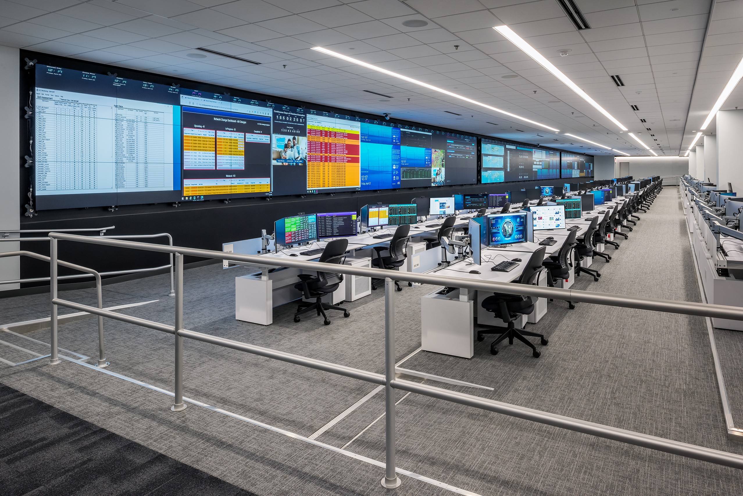 a large room with lots of computers and large screens with graphics and data on them