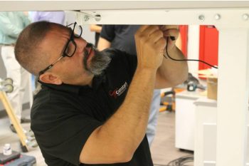 A Constant Technologies Installation team member working with wires under a console