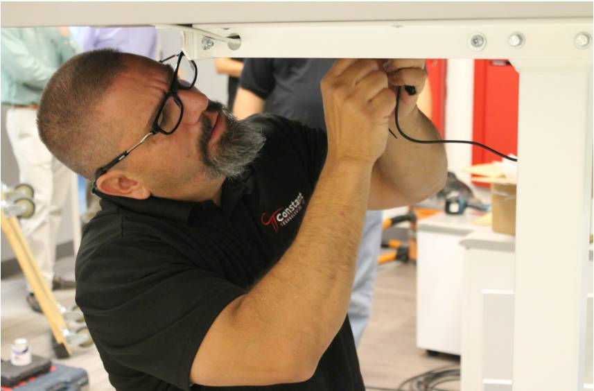 A Constant Technologies Installation team member working with wires under a console