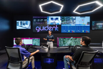 a woman giving a presentation in front of a sign that says guident