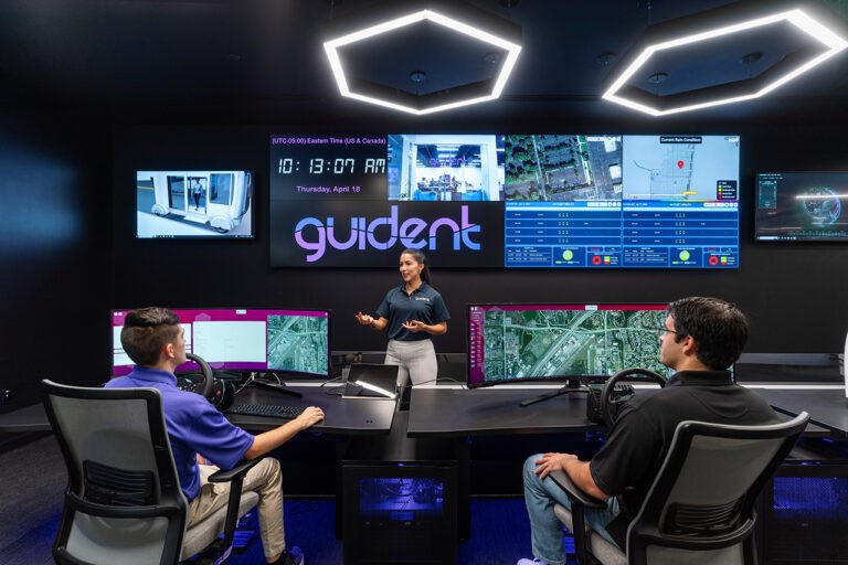 a woman giving a presentation in front of a sign that says guident